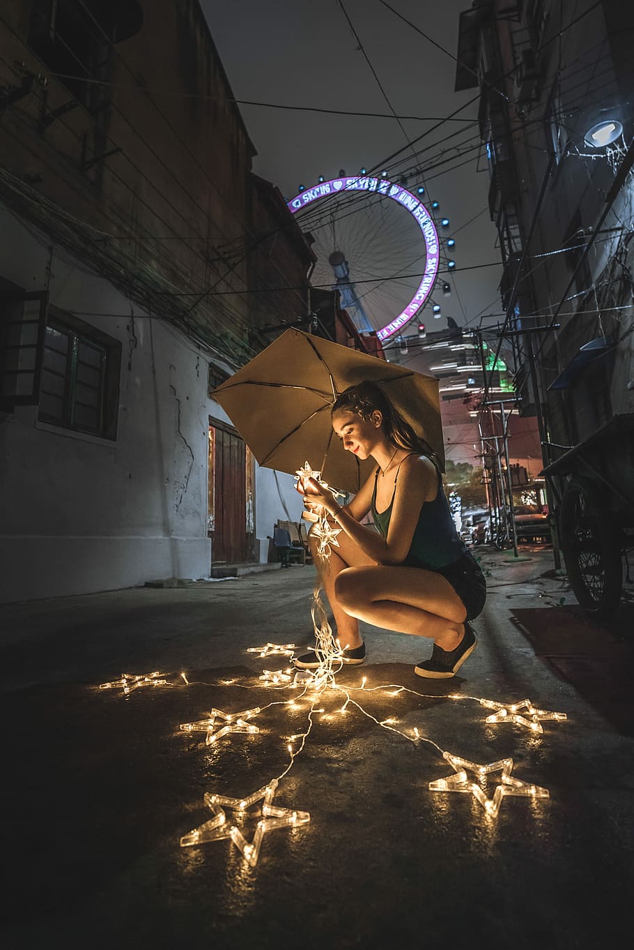 woman holding umbrella and string lights during nighttime, woman holding star lights outdoors