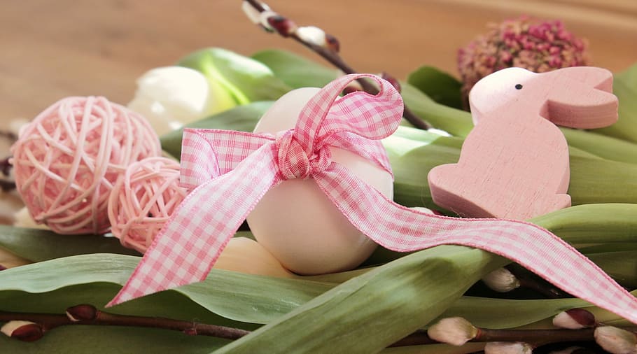 white and pink Easter bunny-themed decoration on green leaf, easter egg
