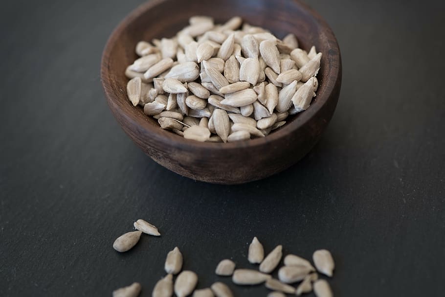 round brown container with gray seeds, sunflower seeds, cores