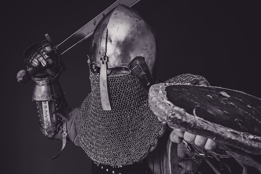 man with steel and chainmail armor holding sword, person holding sword in grayscale photography