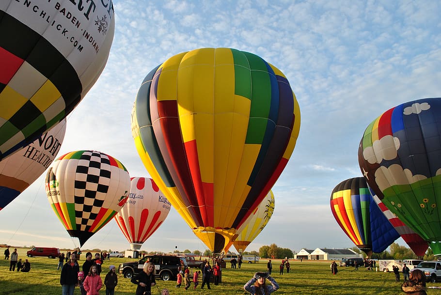 people standing in open field with hot air balloons, ballooning