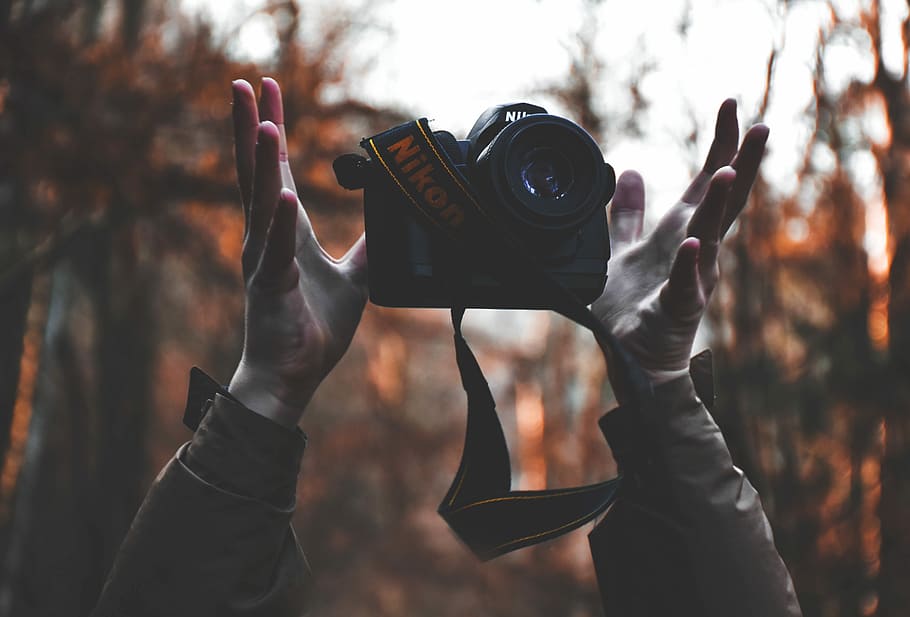 person tossing upward black Nikon DSLR camera taken at daytime, person holding Nikon DSLR camera HD wallpaper