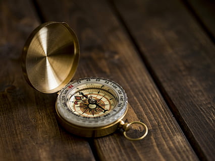 shallow focus photo of compass, gold-colored compass on brown panel HD wallpaper