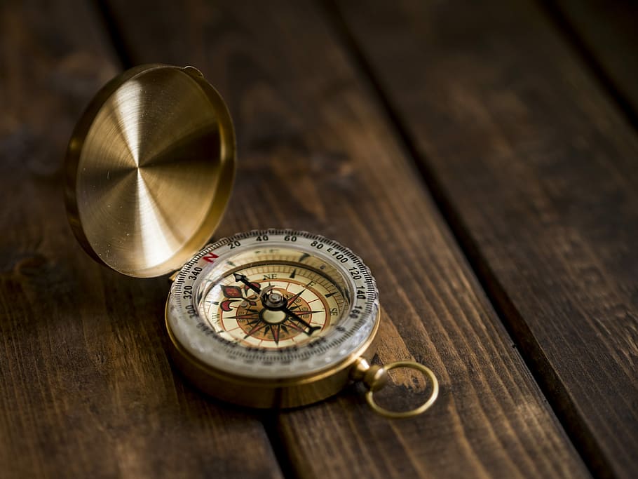 shallow focus photo of compass, gold-colored compass on brown panel HD wallpaper
