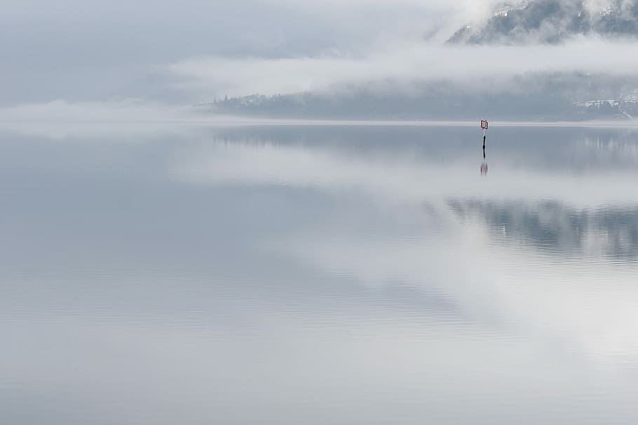 landscape photography of foggy body of water, wooden sign in body of water near mountain HD wallpaper