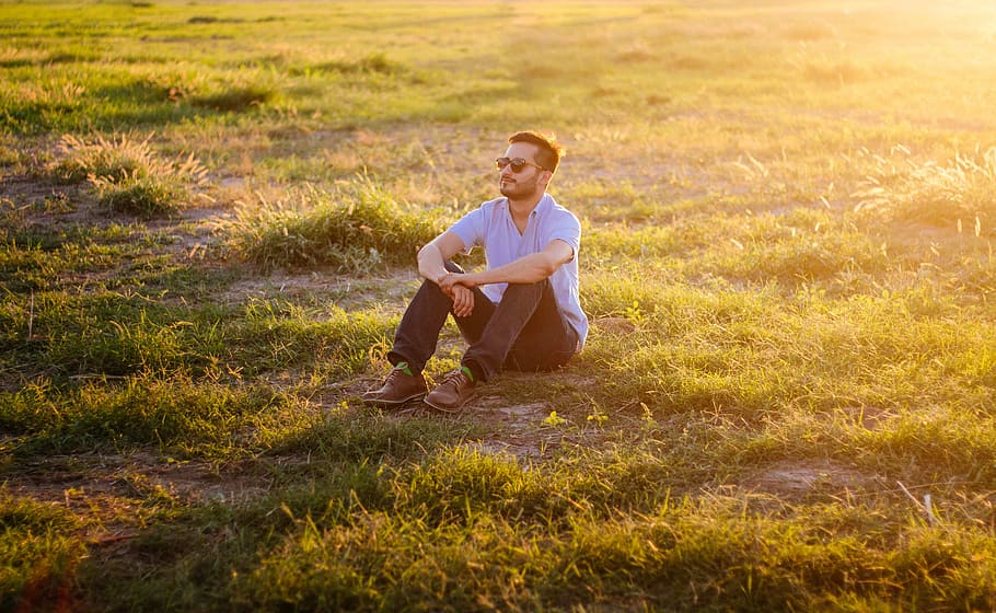 man sitting on green grass field, man sitting on green grass