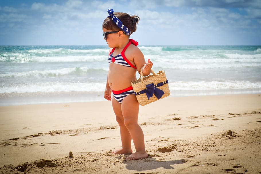 girl carrying beige wicker basket on beach shore during daytime HD wallpaper