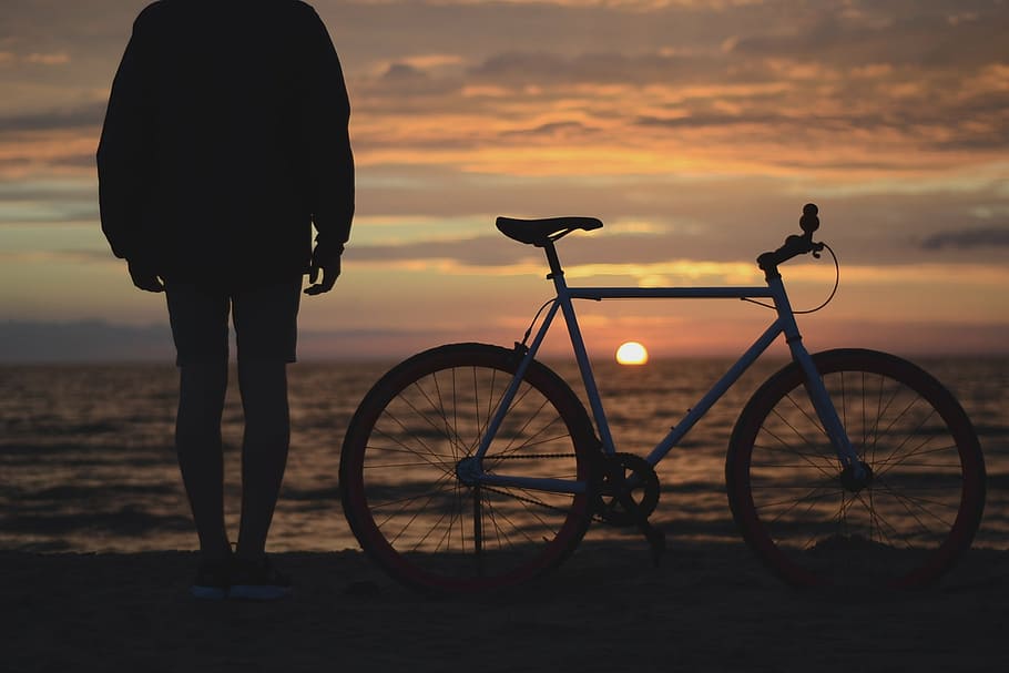 man standing bed bike on sea shore, person, beach, watching, sunset, HD wallpaper