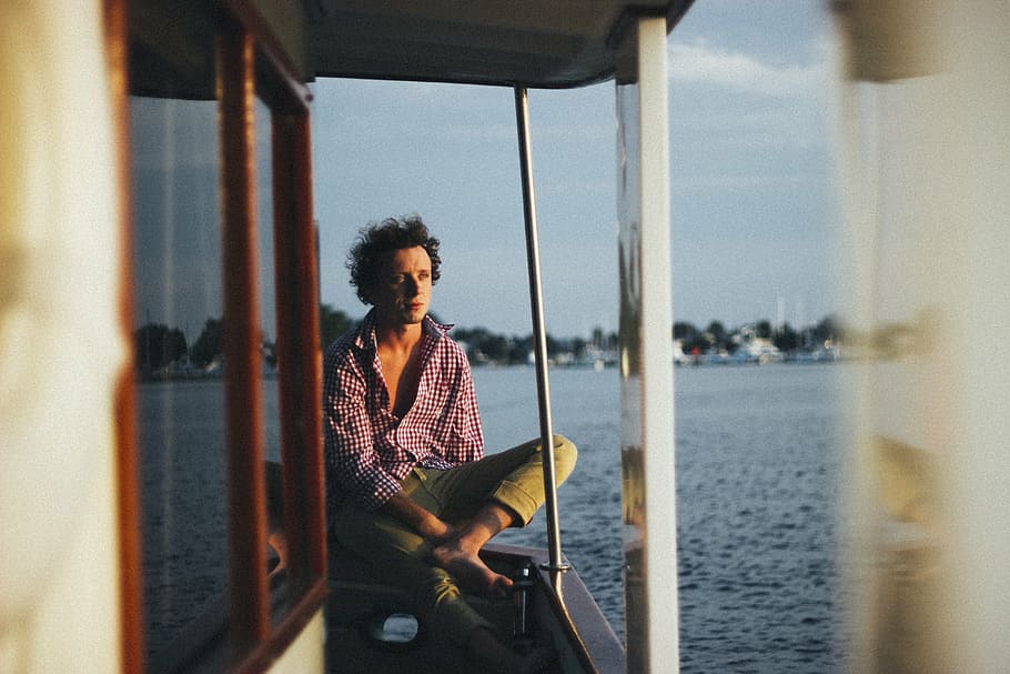 man sitting on boat railing under blue sky at daytime, men HD wallpaper