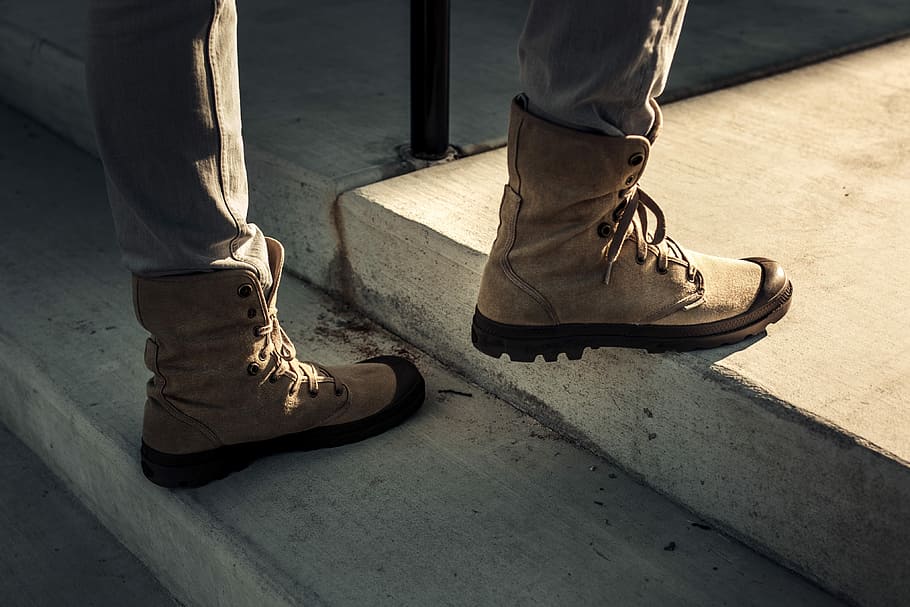 man walking on concrete staircase, person wearing brown boots