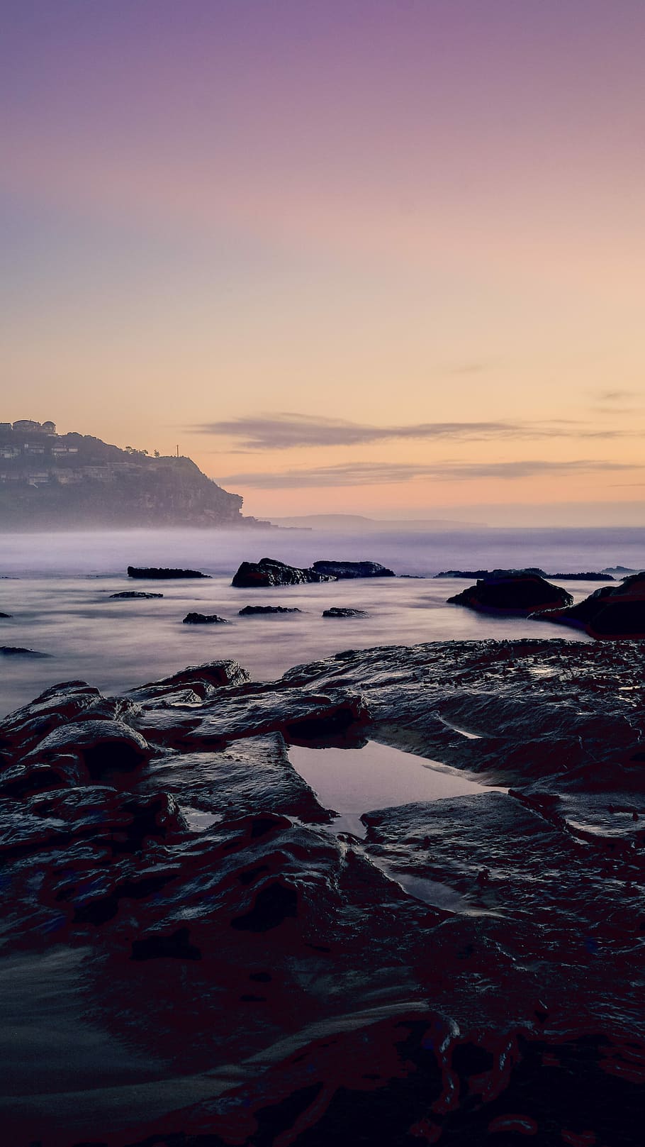 black and gray big rocks beside body of water near mountain under gray sky at golden hour HD wallpaper