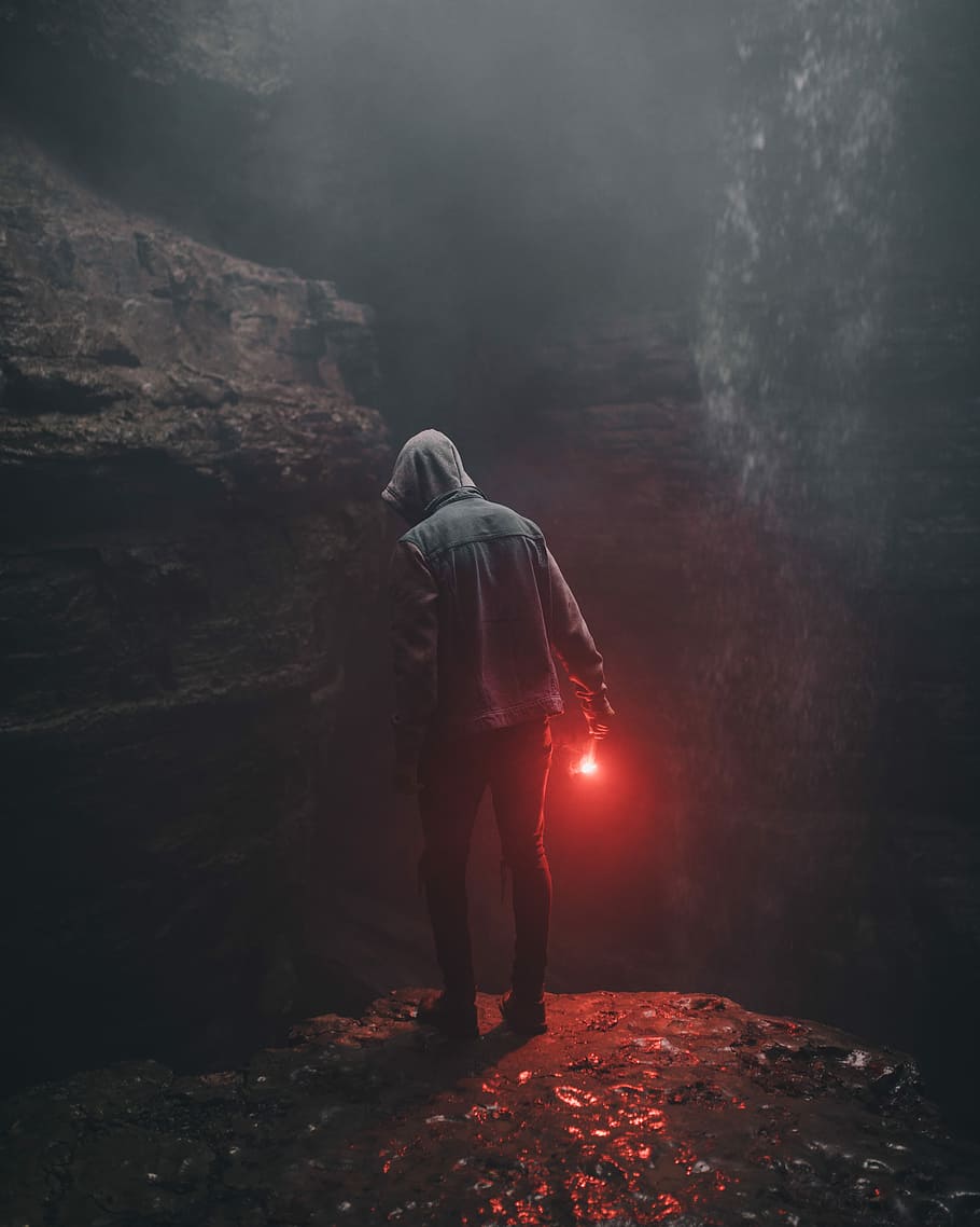 man wearing hoodie holding red light in right hand, person holding light looking below, HD wallpaper
