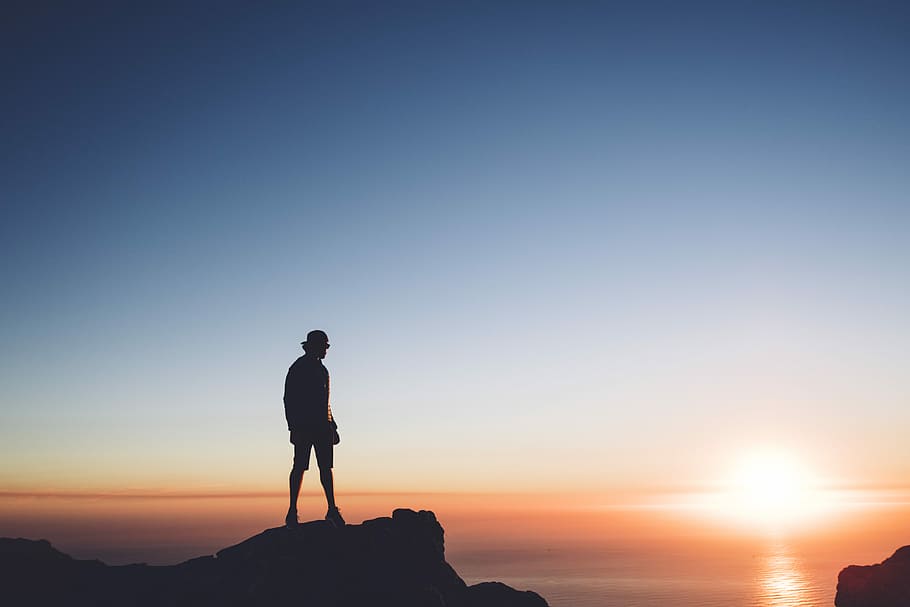 silhouette photo of man standing on peak front of the sea, man on top of mountain HD wallpaper