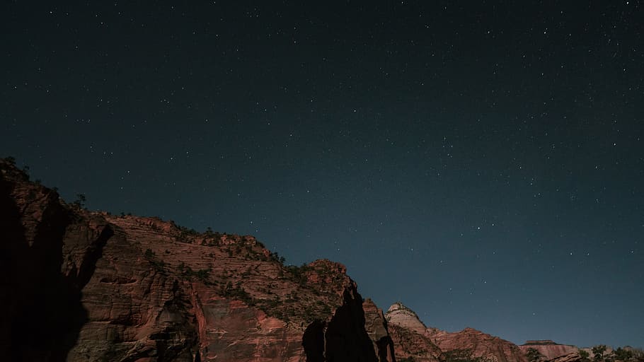 low-light photo of rock formation, brown rocky mountain under blue sky during daytime HD wallpaper