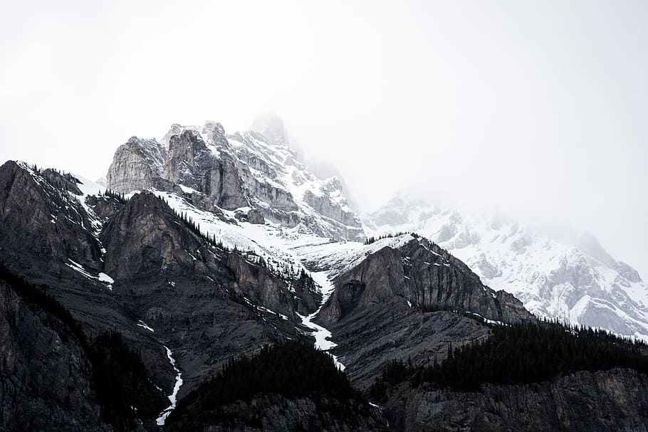 landscape photography of mountains covered with snow, gray mountains covered by snow surrounded by green trees during daytime high-angle photography HD wallpaper