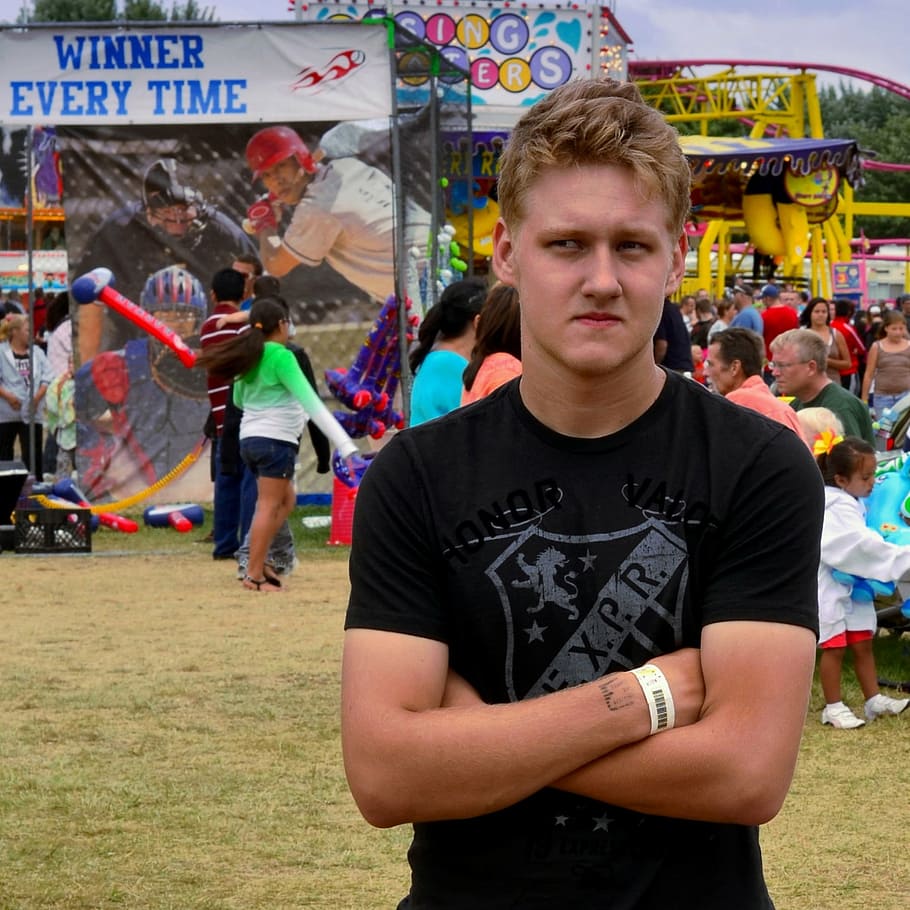 man crossing arms while standing near carnival at daytime, boy