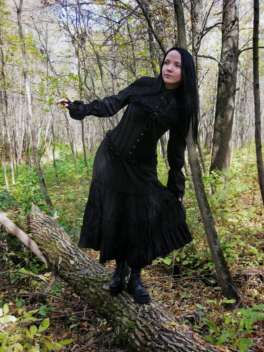 woman wearing black dress standing on brown tree log, stock, model