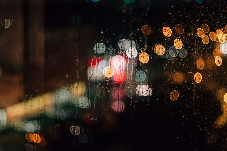 A rain-streaked window with a bokeh effect, clear glass panel HD wallpaper