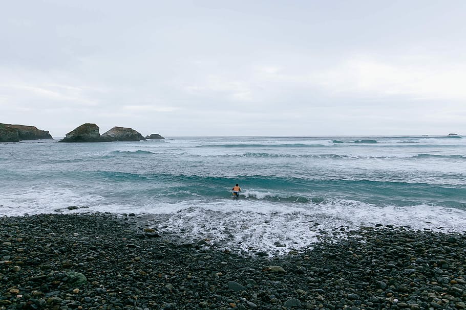 landscape photography of coastline, person standing on shoreline facing the crashing sea waves HD wallpaper