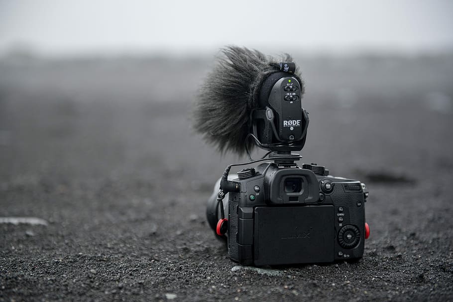 grayscale photo of DSLR camera on sand, black camera on grey soil