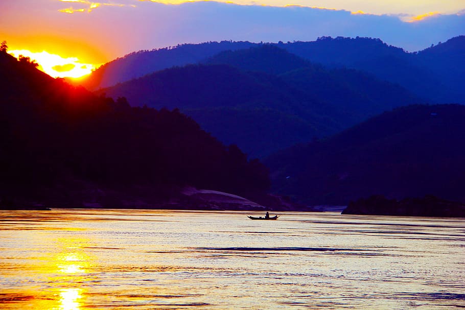 person riding on boat at body of water with mountains as background HD wallpaper