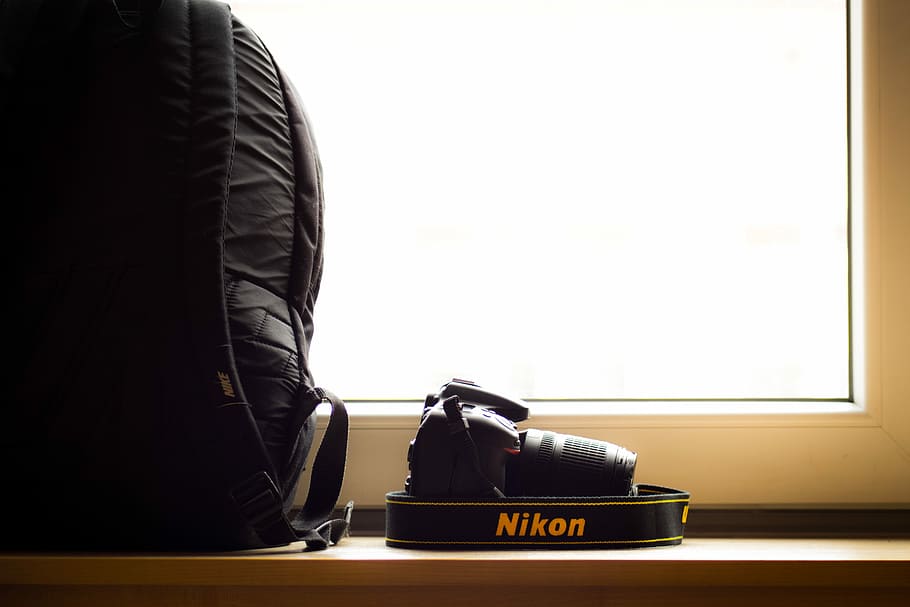black Nikon DSLR camera beside black backpack, black Nikon DSLR beside bag HD wallpaper