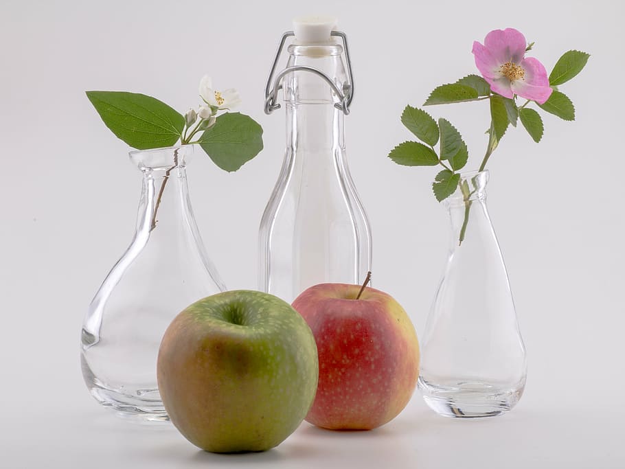 two apple fruits beside three glass bottles, still life, flowers