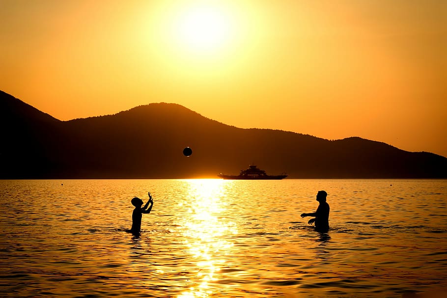 silhouette of two people playing ball on water during sunset, HD wallpaper
