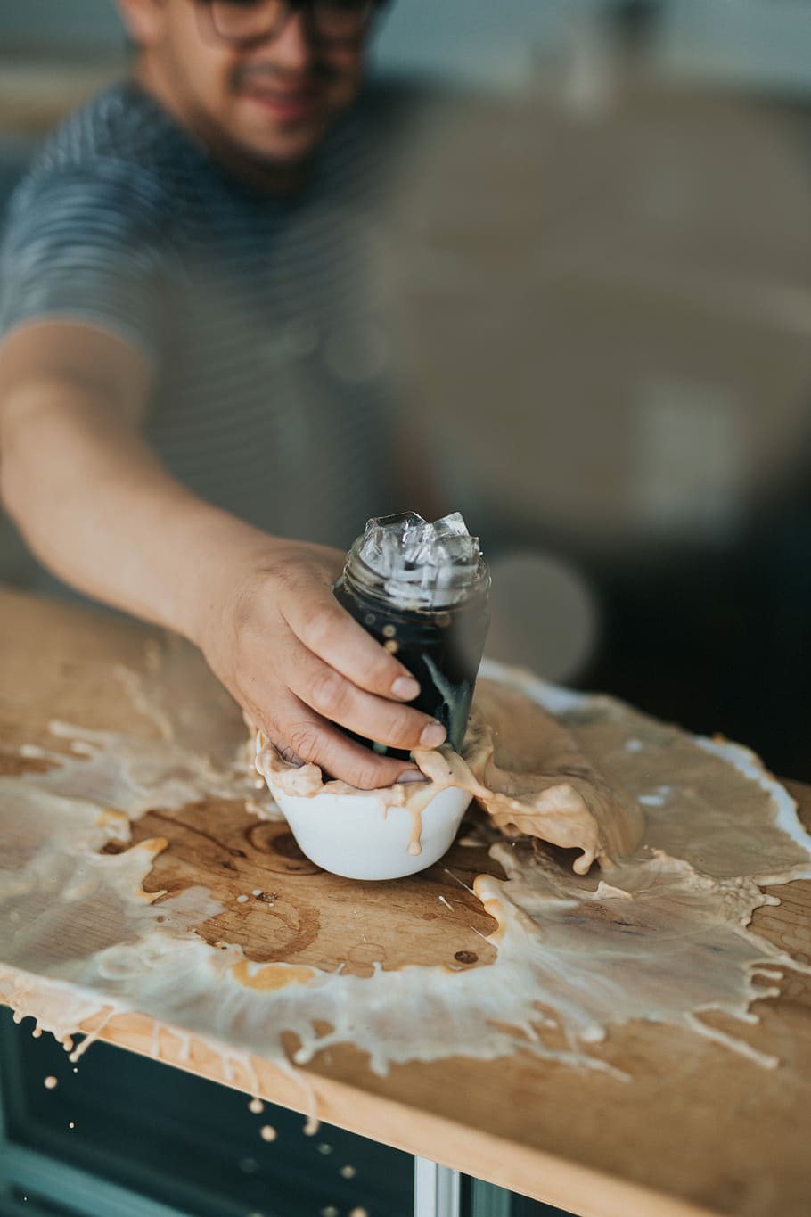 man holding clear glass jar putting on white ceramic bowl on brown wooden table, person holding clear glass jar filled with ice on white ceramic mug with spilled coffee on brown wooden table inside room HD wallpaper