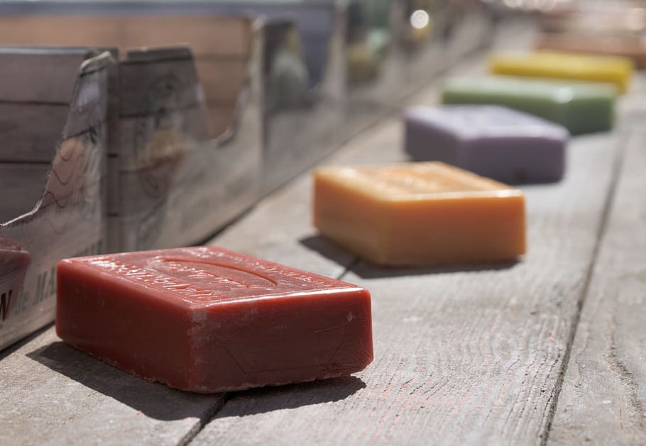 closeup photography of five assorted-color soaps on gray wooden plank
