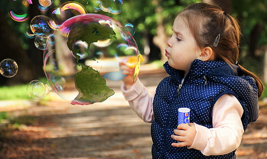 girl wearing blue and white polka-dot vest blowing bubbles during daytijme HD wallpaper