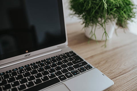 Silver Acer laptop on a wooden desk with a green plant, pencils and an Apple iPhone HD wallpaper
