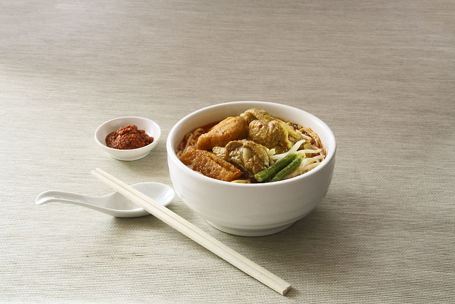 white ceramic bowl filled with cooked noodles near white chopsticks, noodle in bowl