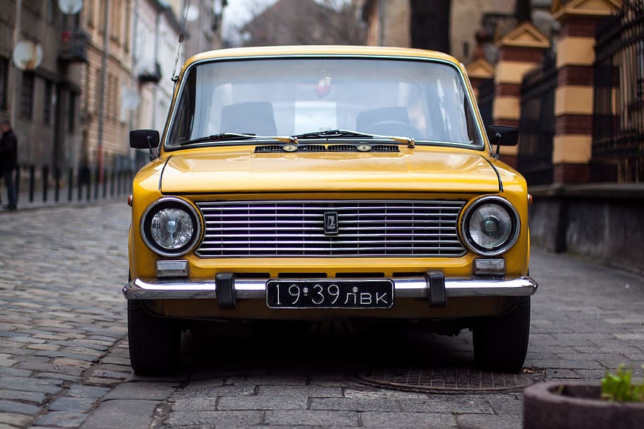 yellow car between building, yellow Lada Vaz parked during daytime HD wallpaper