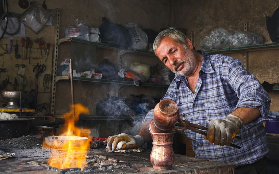 man holding brown hand tool, man holding melting pot near flame HD wallpaper