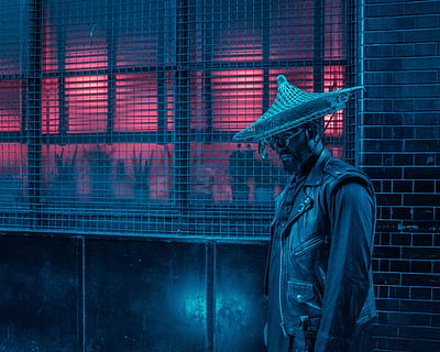 man wearing black vest standing beside window screen outside the building, man wearing leather jacket with conical hat standing near wall HD wallpaper