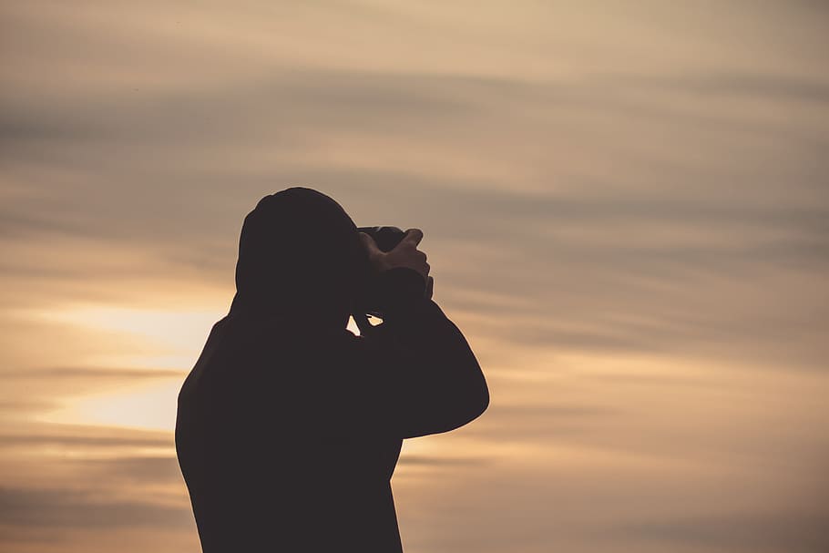 person using camera fronting the sky, silhouette of person taking pictuer