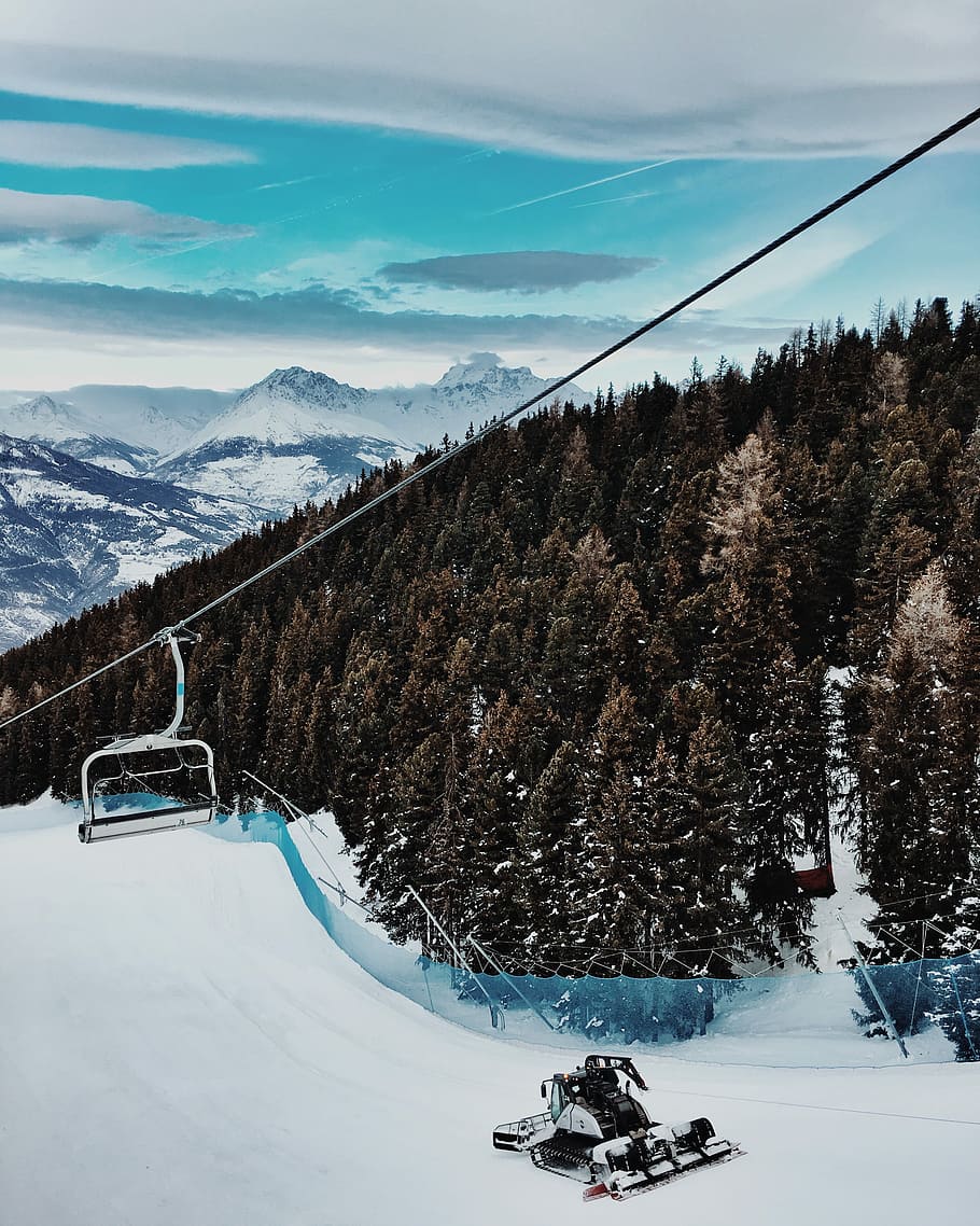 scenery of mountain and trees, snow vehicle near trees below ski lift in distant of snow capped mountains HD wallpaper