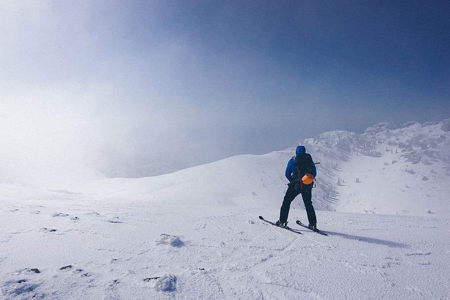 man wearing blue jacket standing on snow near mountain, winter HD wallpaper