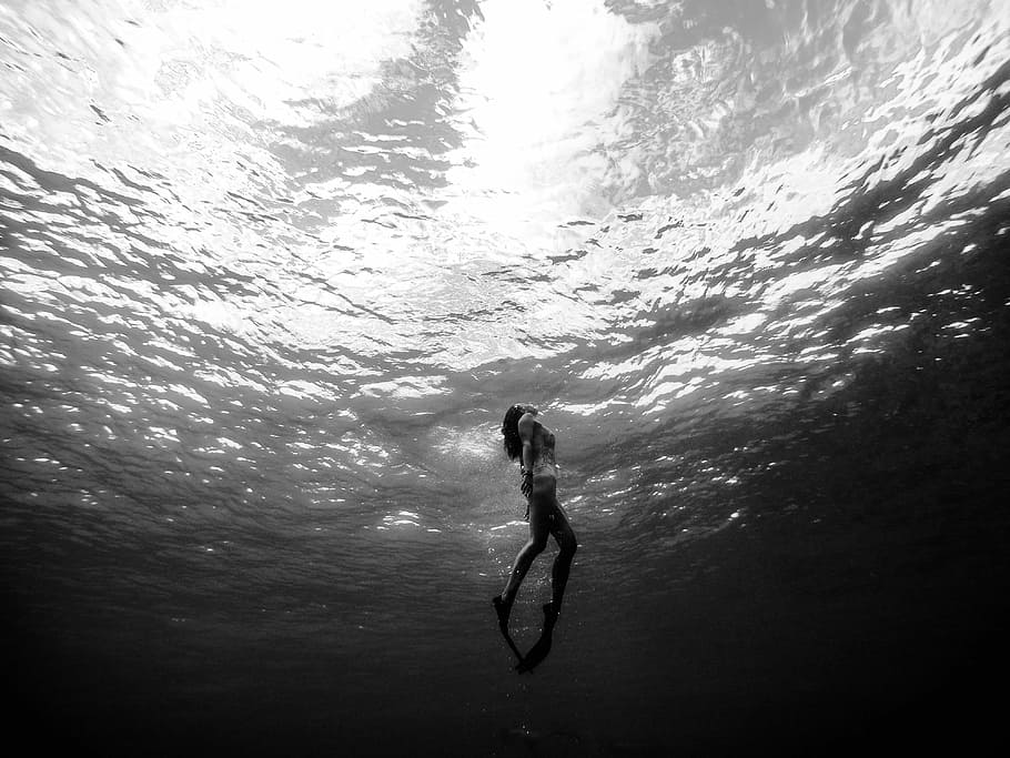 woman diving underwater, grayscale photography of woman underwater
