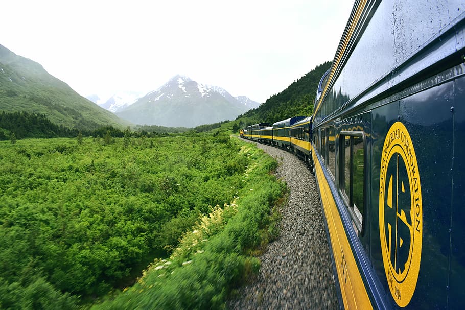 train near mountains, blue and yellow train surrounded by mountains at daytime HD wallpaper