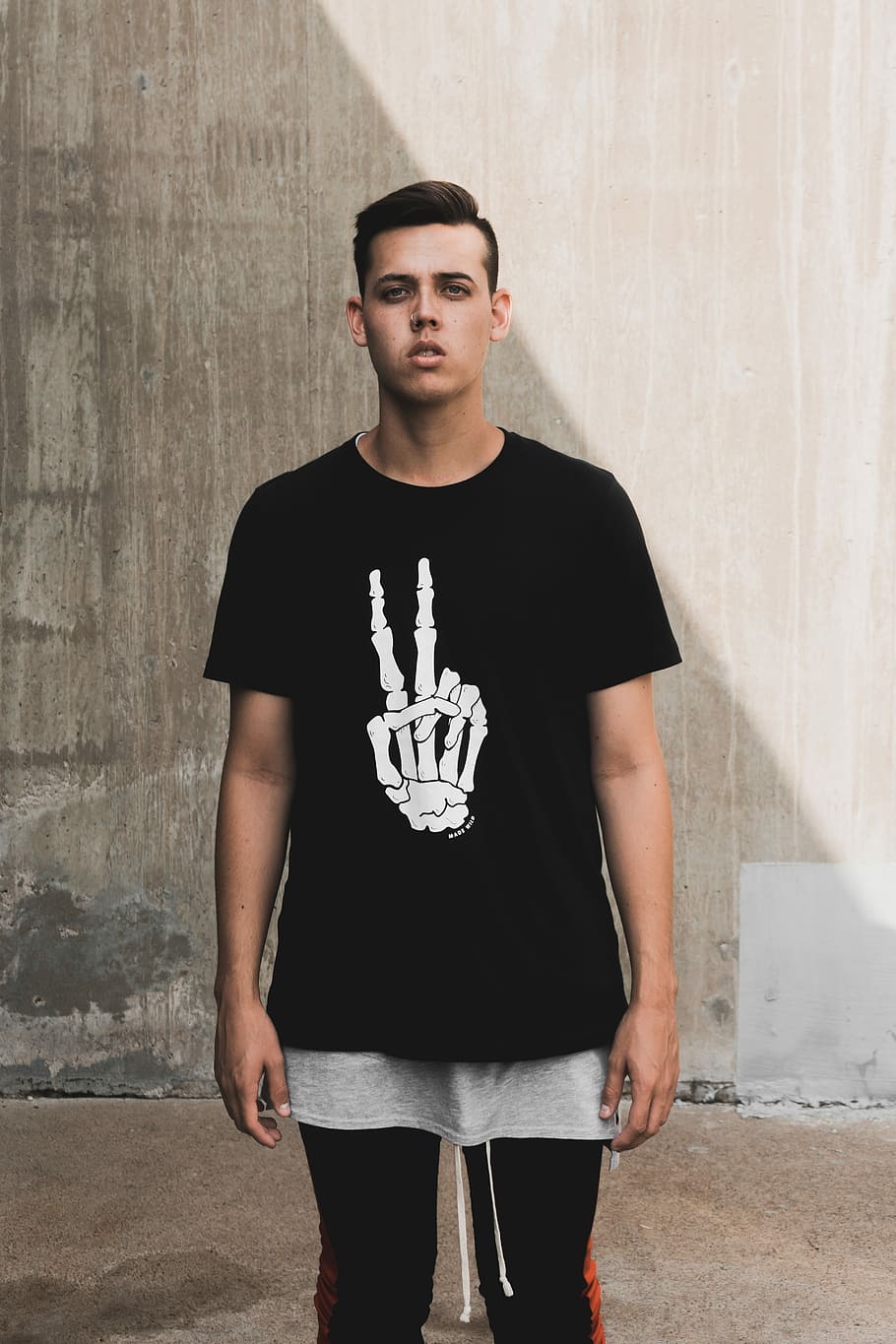 man standing near wall, man wearing black and white peace skeleton hand print crew-neck t-shirt while standing, HD wallpaper