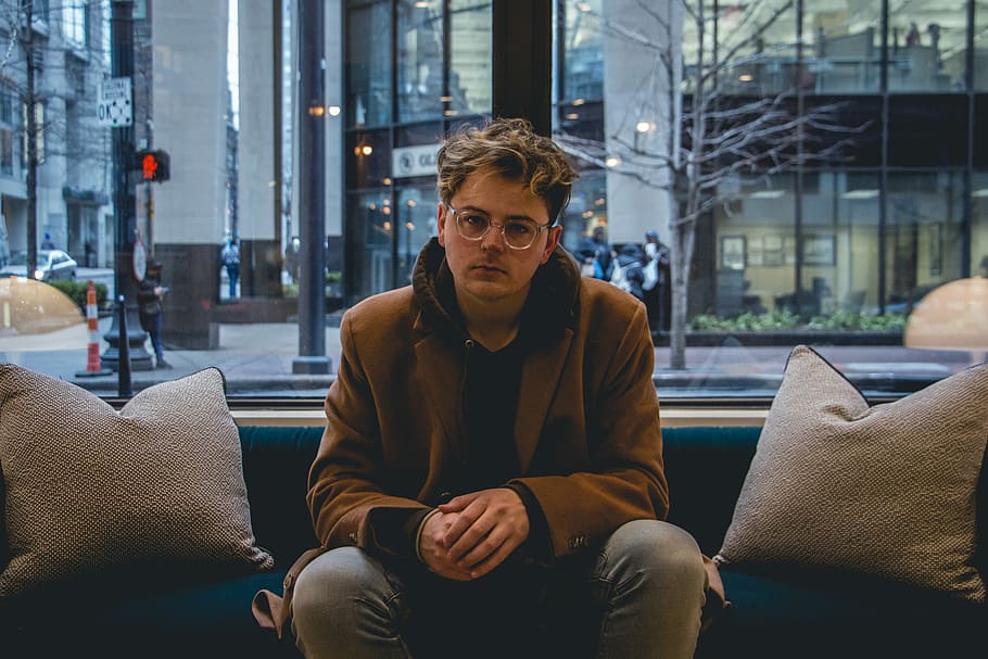 man wearing brown coat sitting on sofa during daytime, man wearing brown coat sitting on blue sofa HD wallpaper