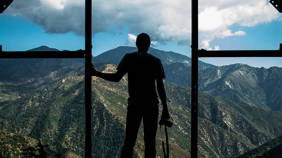 silhouette photo of person standing near door overlooking mountain during daytime, silhouette photography of man holding DSLR camera HD wallpaper