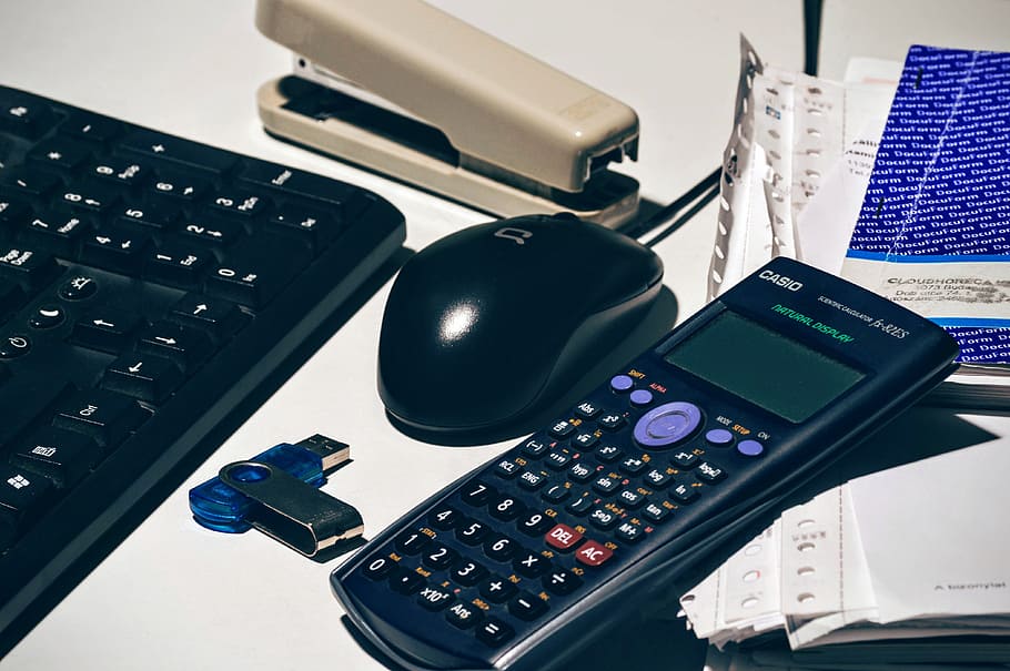 Casio scientific calculator next to mouse, accounting, flash drive
