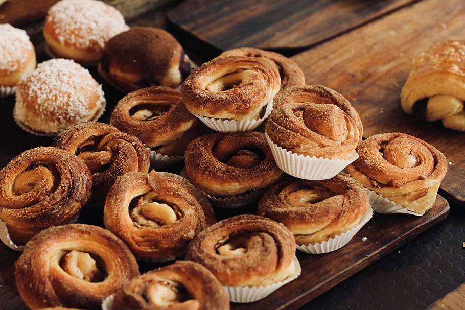 bunch of cinnamon swirl bread, muffins on top of brown wooden boards HD wallpaper