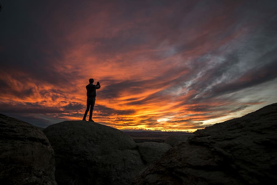 man standing on rocks under cloudy sky, silhouette of man on cliff HD wallpaper