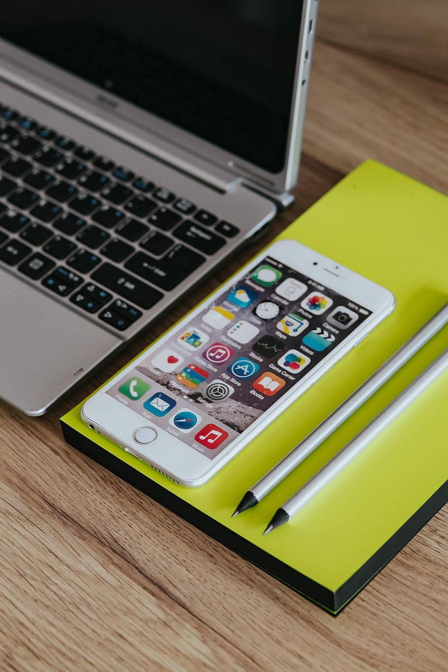 Silver Acer laptop, a white Apple iPhone and a notepad on a wooden desk HD wallpaper