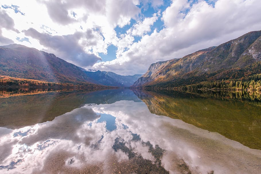 Clouds mirrored in a mountain lake, panoramic photo of lake between two mountains under thick white clouds HD wallpaper