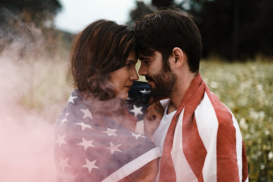 man standing in front of woman covered with U.S.A. flag, selective photography of man and woman face to face covered with U.S.A. flag